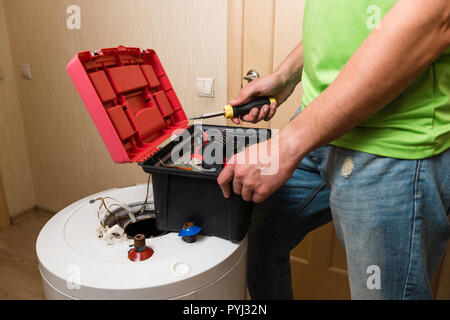Male plumber perair old boiler with screwdriver indoors Stock Photo