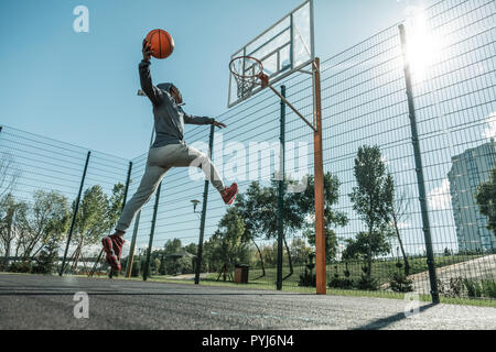 Nice strong man jumping while throwing a ball Stock Photo