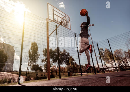 Handsome Afro American man throwing a ball into the basket Stock Photo