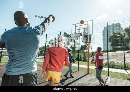 Handsome skilled man throwing a ball from the distance Stock Photo