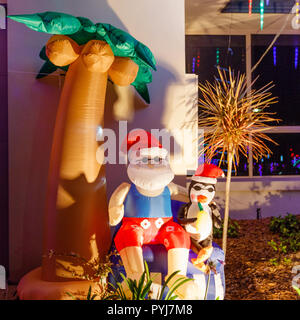 Inflatable Santa Clause and penguin under palm tree at CHRISTMAS LIGHTS festival in Queensland, Australia. Australian suburbs. Stock Photo