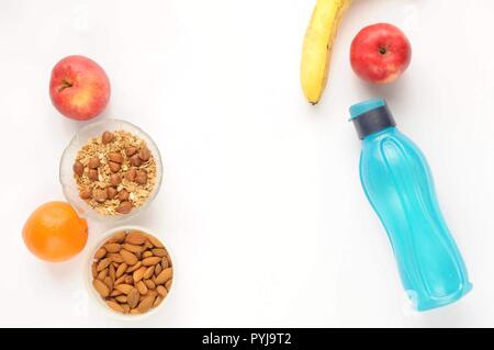Attributes of a healthy lifestyle: food, sports and athlete's equipment on white background. Flat view with copy space. Eco bottle, nuts, oatmeal and Stock Photo