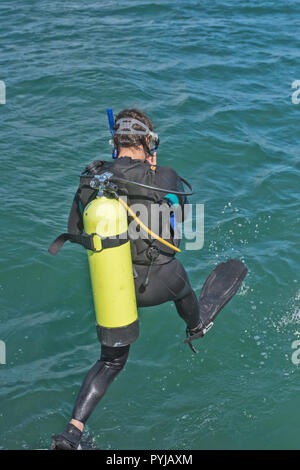 Scuba diver in wetsuit entering water from boat Stock Photo