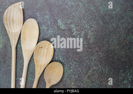 angled wooden spoon corner border on a blue green counter top Stock Photo
