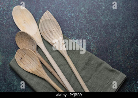 horizontal wooden spoons and green kitchen towel on blue green counter top Stock Photo
