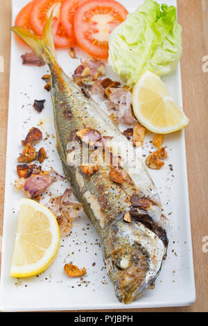 A scad, Trachurus trachurus, also known as a scad mackerel or horse mackerel, that has been caught on rod and line and fried with chopped garlic and s Stock Photo