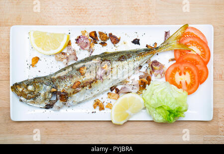 A scad, Trachurus trachurus, also known as a scad mackerel or horse mackerel, that has been caught on rod and line and fried with chopped garlic and s Stock Photo
