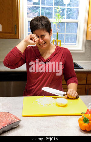 Woman bawling her eyes out while cutting an onion in the kitchen Stock Photo