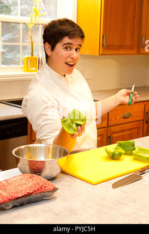 Woman in a chef coat showing off her vegetables while cutting in the kitchen Stock Photo
