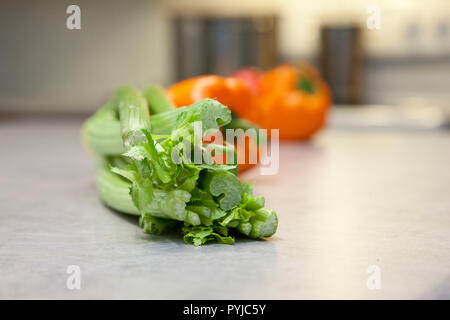 Fresh crunchy green celery stalks and round ripe tomatoes on the kitchen counter Stock Photo