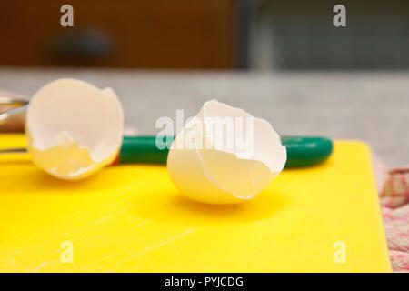 Cracked egg shells sit on a plastic cutting board in the kitchen Stock Photo