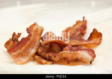 Delicious cooked bacon sits on a white paper towel ready to be eaten Stock Photo