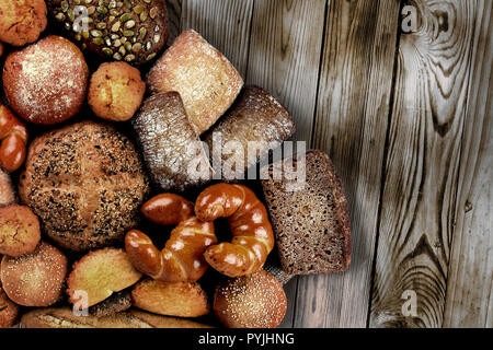 Variety of bread products on dark wooden background in vintage style. Creative flatlay composition. Copy space Stock Photo