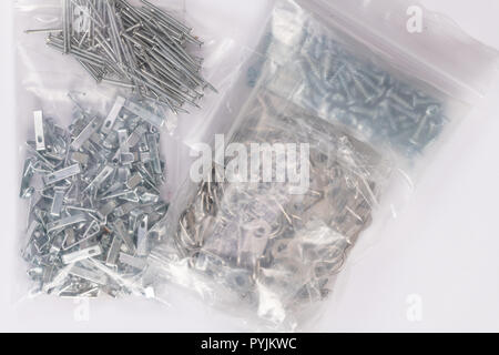Groups of frame hanging metal plates, hooks, and nails isolated on white. frame hanging metal plates, hooks, nails, and screws in plastic packages iso Stock Photo