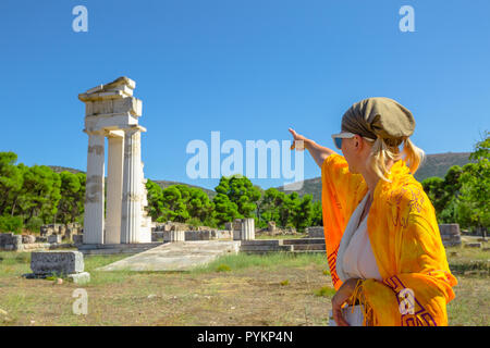 Greek dressed woman in indicates the ruins of Temple of Asklepieion, Epidaurus, Peloponnese, Greece. The Sanctuary of Asclepius is a famous heritage site.Mediterranean travel and tourism concept Stock Photo