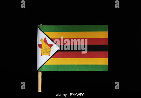 A national flag of Zimbabwe on toothpick on black background. Flag contain five colours. Red, black, green, yellow, white. Stock Photo