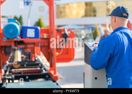 Worker pressing buttons on CNC machine control board in factory. Stock Photo