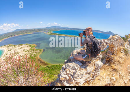 Travel female takes shots of scenic Voidokilia Beach from Navarino Castle ruin in Pylos, Peloponnese, Greece after hiking.Hiker woman photographing a popular greek landmarks. Fish eye view Stock Photo