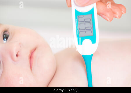 Baby sick with measuring electric thermometer. Child fever ill. Kid catch cold with temperature. Sick child in bed with fever measuring temperature wi Stock Photo