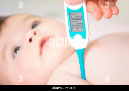 Baby sick with measuring electric thermometer. Child fever ill. Kid catch cold with temperature. Sick child in bed with fever measuring temperature wi Stock Photo