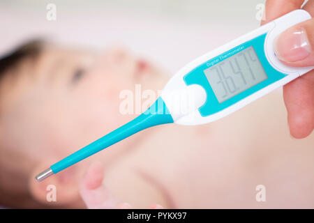 Baby sick with measuring electric thermometer. Child fever ill. Kid catch cold with temperature. Sick child in bed with fever measuring temperature wi Stock Photo