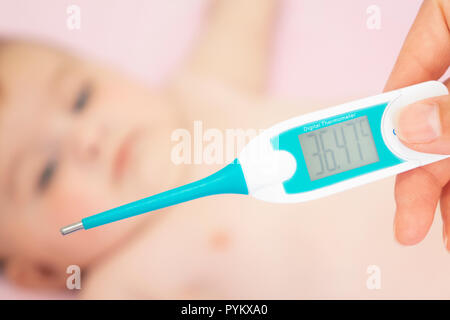 Baby sick with measuring electric thermometer. Child fever ill. Kid catch cold with temperature. Sick child in bed with fever measuring temperature wi Stock Photo