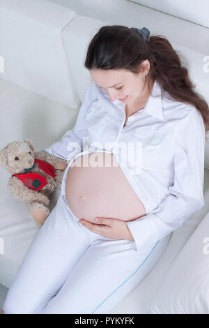 closeup.beautiful pregnant woman with a soft toy lying on the couch. Stock Photo