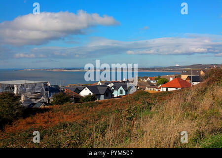 Looking across the rooftops of Ogmore by sea towards Porthcawl with swansea bay in the far distance with steam rising from Port Talbot steelworks. Stock Photo