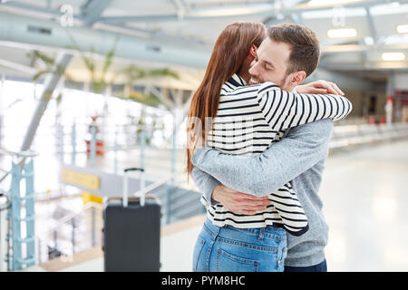 Young happy couple hugs each other while reunion after the trip at the airport Stock Photo
