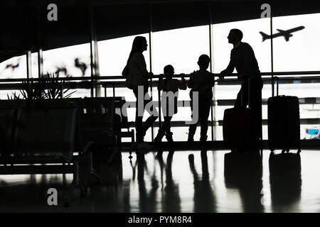 Silhouette of family with two children at the airport in front of airplane Stock Photo