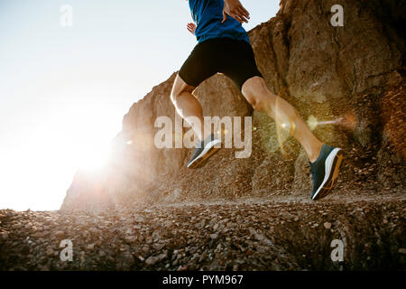 healthy lifestyle middle aged man runner running on mountain trail in sunset Stock Photo