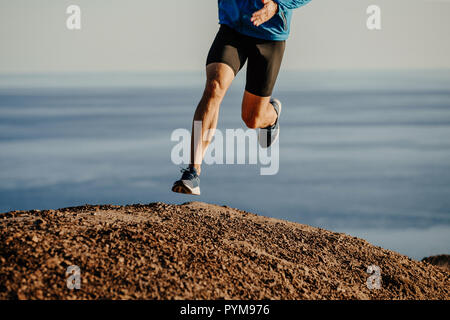 athlete runner running uphill mountain on background of sea Stock Photo