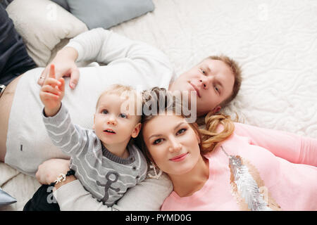 Portrait from above of attractive wife and husband with son lying on bed Stock Photo