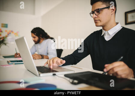 businessman using a digital writing pad while working on laptop computer. Creative business team working in office. Stock Photo