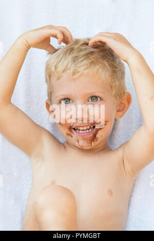 Portrait of fair-haired boy with chocolate on his face isolated on white background,baby boy smile. Stock Photo