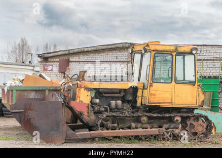 old rusty yellow abandoned tractor with bucket. Stock Photo