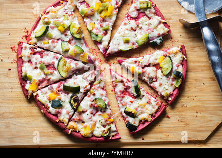 Beetroot base pizza with zucchini, smoked ham, cheese & red onion Stock Photo