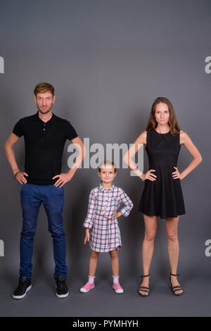 Young happy family bonding together against gray background Stock Photo