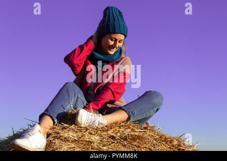 Beautiful modern urban young woman wearing  blue knitting hat, pink coat and jeans. Trendy teenage girl in autumn outdoors. Stock Photo