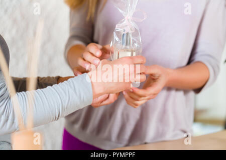 Woman giving perfume gift to her friend Stock Photo