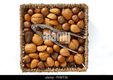 Mixed nuts in a woven basket with nut cracker Stock Photo