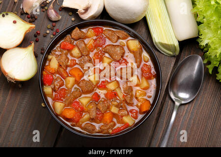 Beef stew in black bowl on wood background, top view goulash soup over grunge wood background Stock Photo
