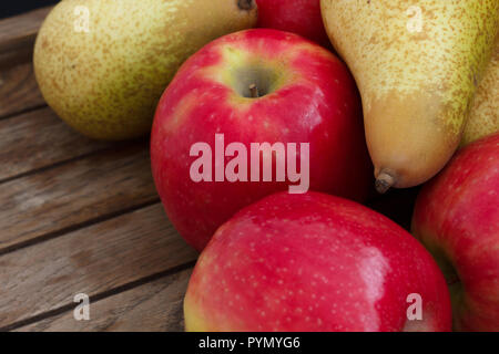 Mixed red apples and pears attractively arranged on dark wood. Stock Photo