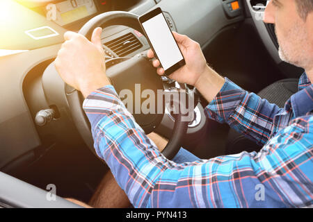 Driver driving a vehicle consulting a phone. Concept of the danger of the use of mobiles in conduction. Elevated view. Stock Photo