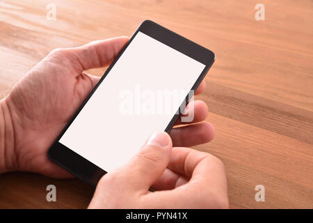 Hands of a man with portable phone in hands on brown wooden isolated table. Elevated view. Horizontal composition. Stock Photo