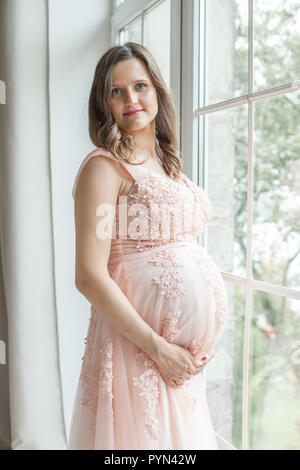 Pregnant woman holds hands on belly. Pregnancy, maternity, preparation and expectation concept Stock Photo