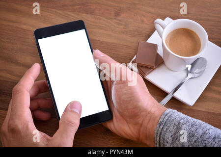Using mobile phone on wood table in rest time with a cup of coffee and chocolate. Top view. Horizontal composition. Stock Photo