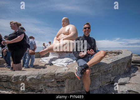 A man makes a humorous pose in front of one of the sculptures at Sydney's Sculpture By The Sea exhibition at Bondi Beach in Australia Stock Photo