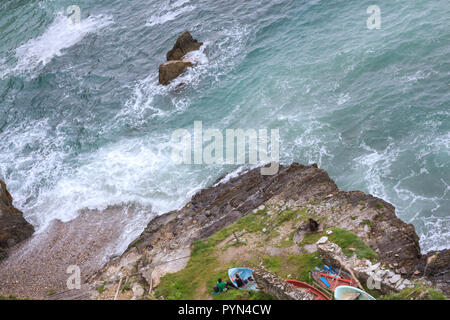 Gueirua beach, Asturias, Spain. Aerial view of rocky beach with waves breaking the shore and a couple in winter clothes sat on some rocks. Stock Photo