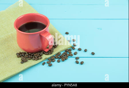 Cup of coffee with coffee beans on blue color wooden background. Stock Photo